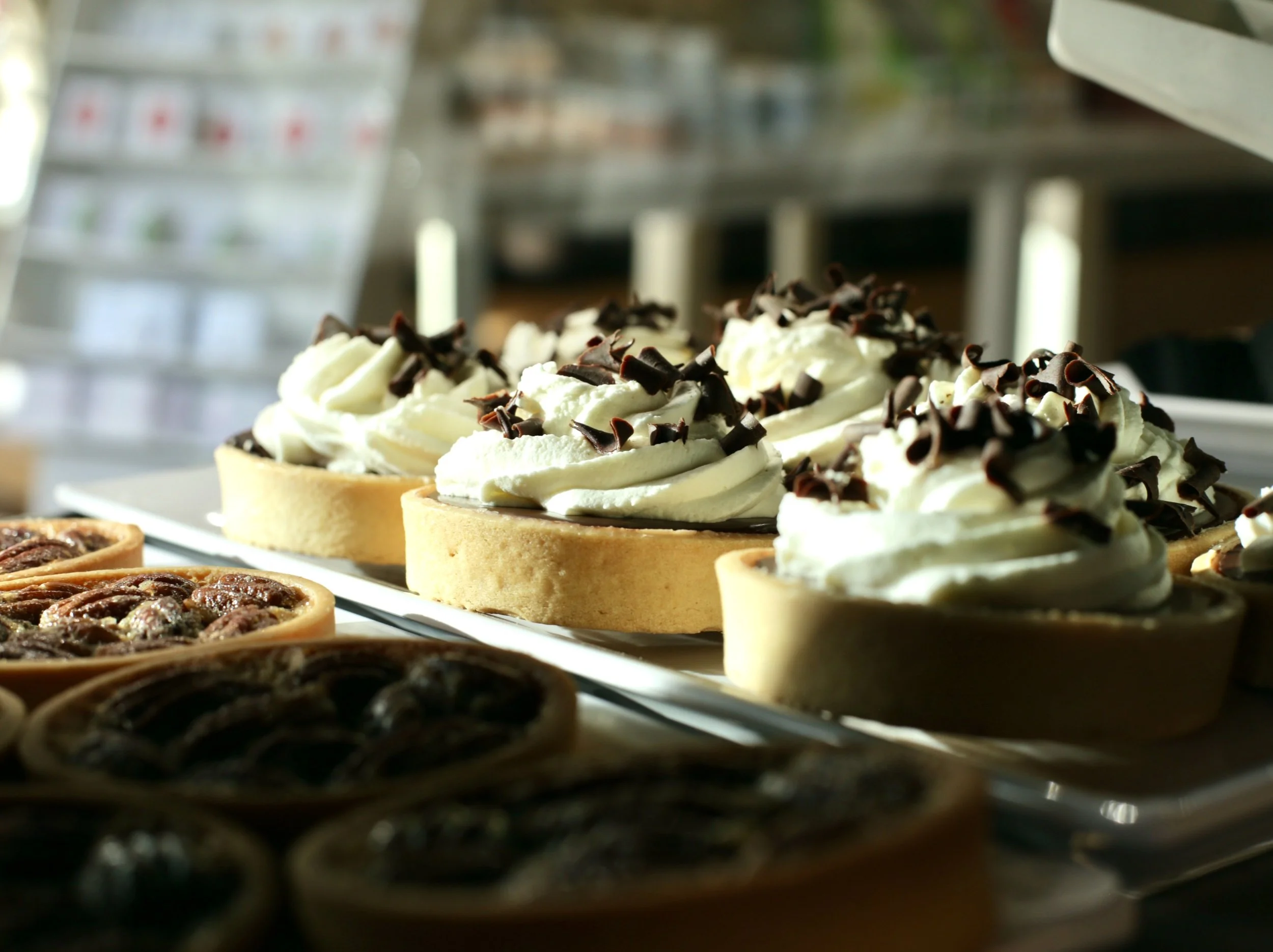 Chocolate Tartlettes: Buttery tart shells with smooth chocolate ganache, piled high with whipped chantilly cream and shaved chocolate curls. For those who prefer elegance by the forkful.