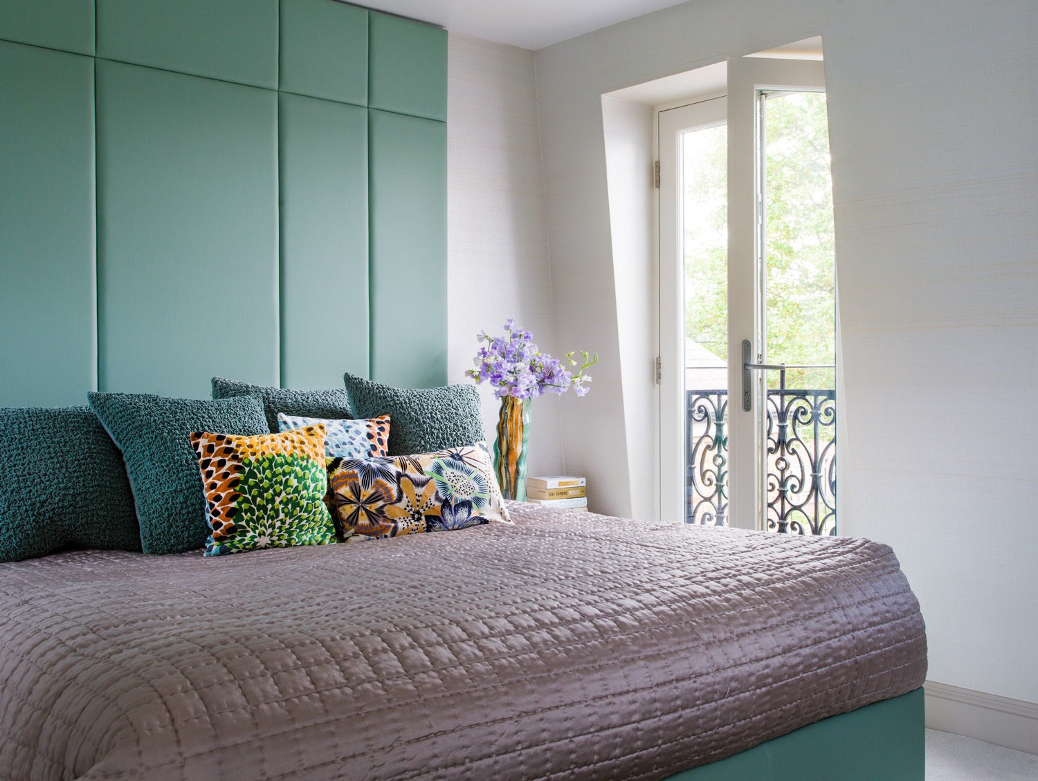 A boutique hotel style bedroom suite was created in the old loft space. Luxurious silver grass cloth wall covering, full height leather headboard and lift up storage base and French doors opening to a view of rear garden creates a tranquil space.