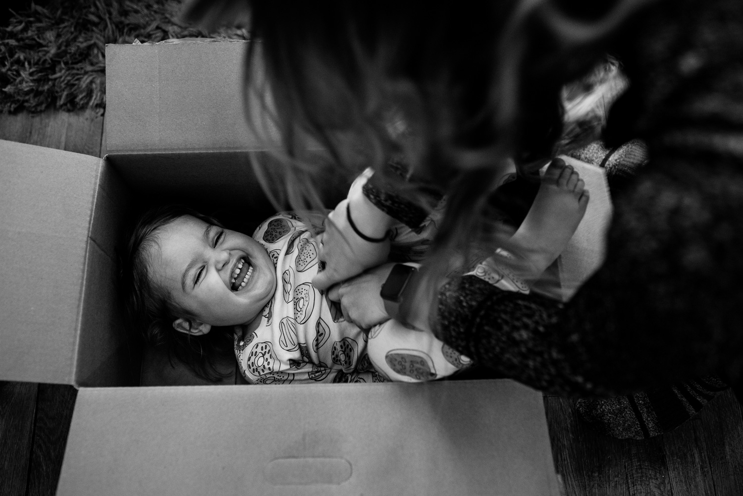 toddler inside a box laughs while being tickled
