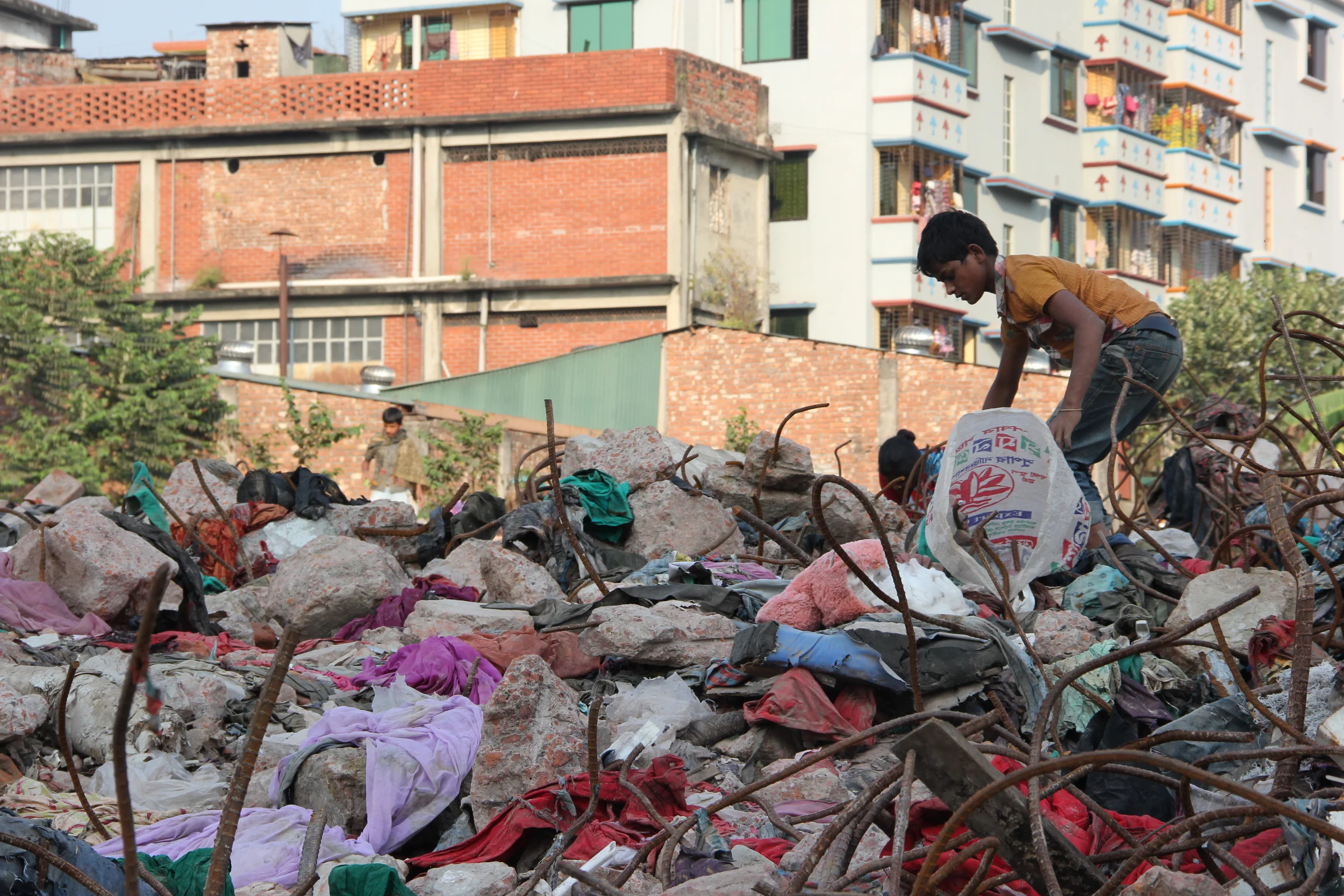 A boy picks over the rubble of Rana Plaza, February 2014. Photo credit: Bishawjit Das.
