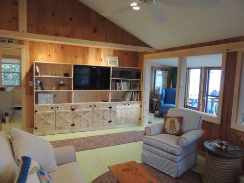 Built ins at this seasonal guest house house the TV, provide storage and a place to display books and family photos.