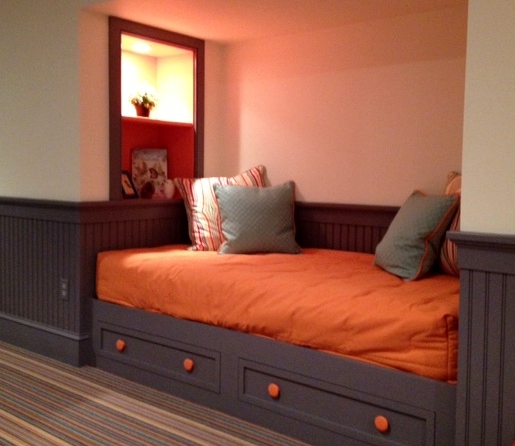 Here is a built in day bed with drawers beneath for storage. Shelves at the end of the bed have an outlet to charge electronic devices. 