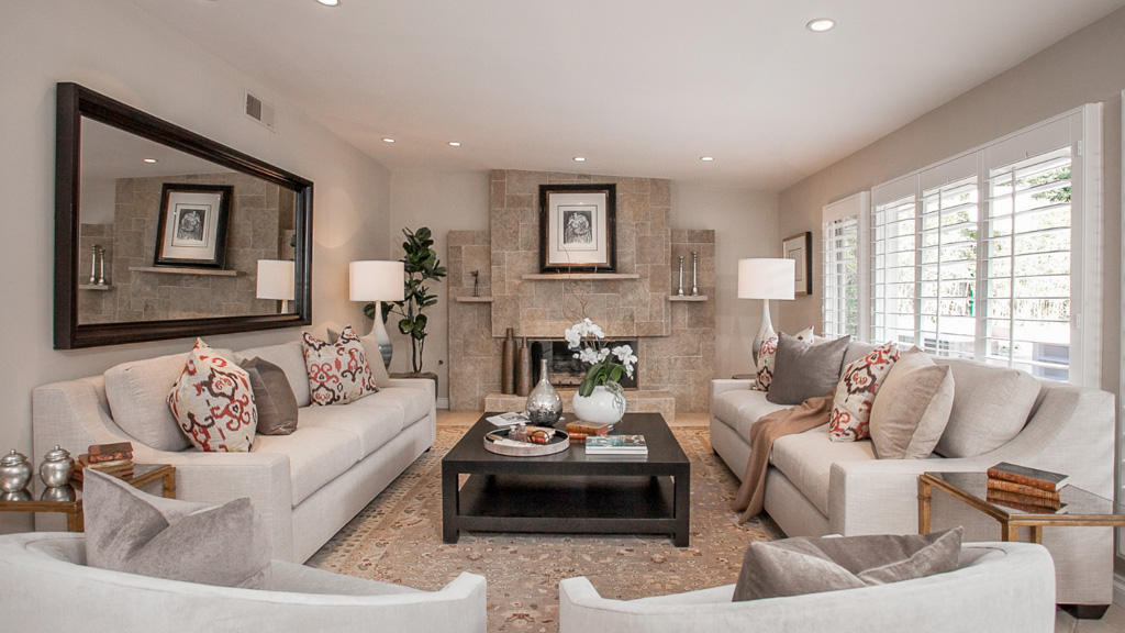 This grand living room's neutral palette is brought to life with just a few throw pillows. Not only do they pop, but notice how they bring out the subtle reds in the rug and warm up the stone fireplace.
