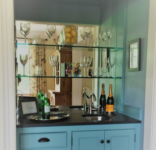 We added mirror glass to the back of this wet bar. It not only reflects the light, but the objects on the shelves. 
