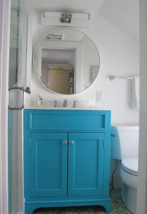 In this tiny bathroom, we selected a bold round mirror with a tiny frame to make the space feel bigger.