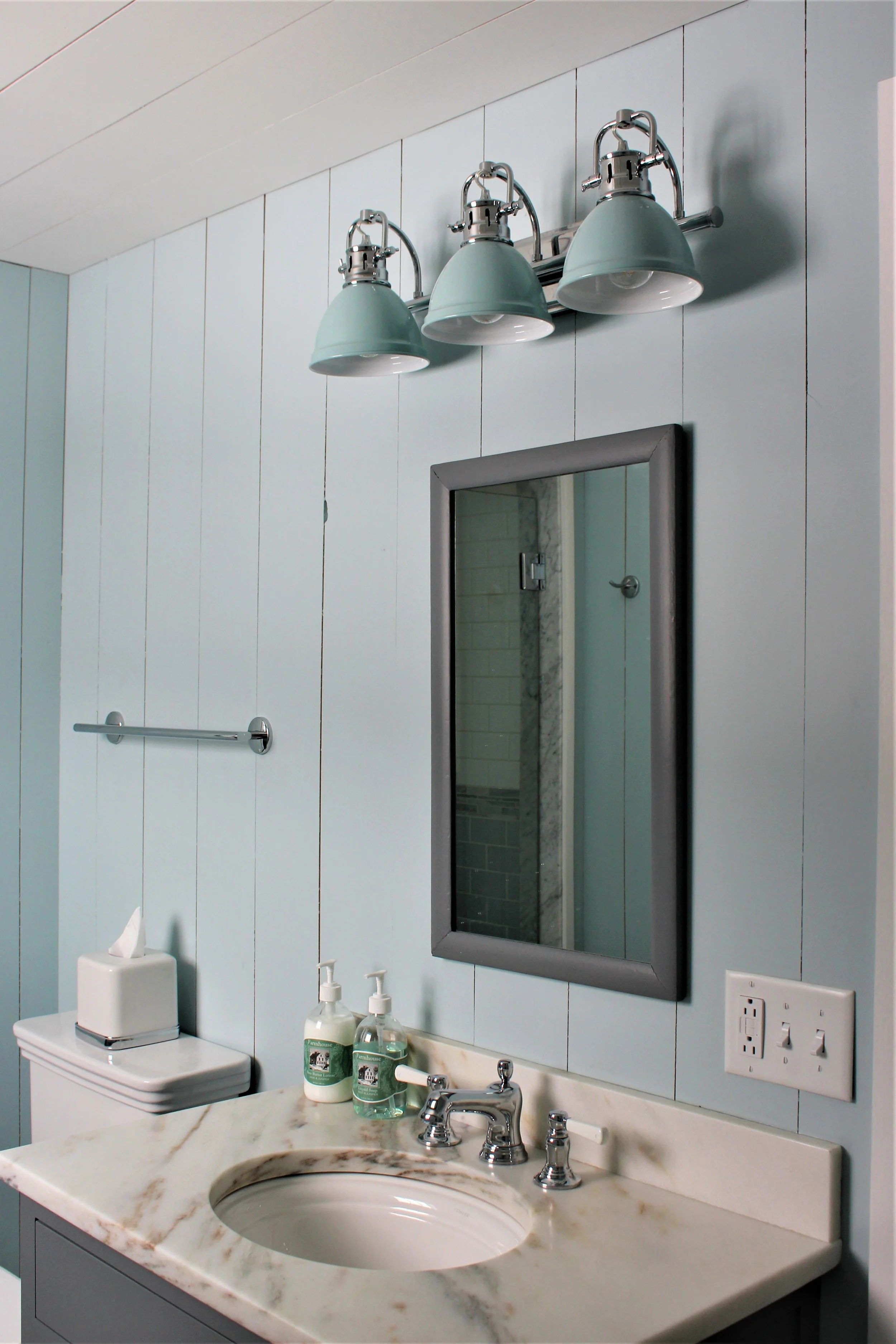 In this tiny bathroom we used a smaller sink in order to have more counter space. We tucked a walk in shower into a corner (you can see the reflection in the mirror). Here we opted for a glass shower door to make the space feel bigger. 