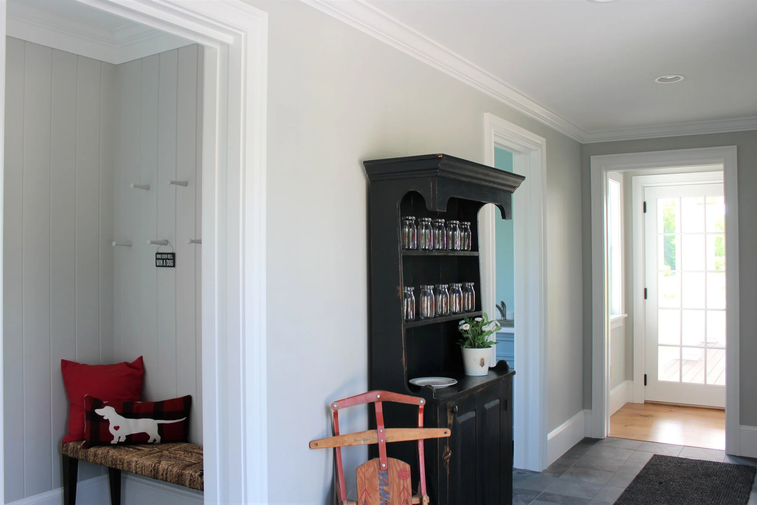 This large foyer has a separate mud room complete with a bench and pegs. The walls are v-grove panels painted the same color as the foyer, Benjamin Moore’s Stonington Grey. The difference in texture adds visual interest.
