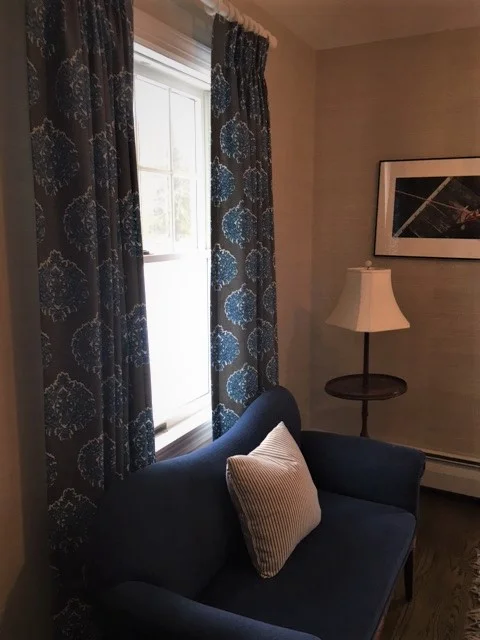 Adjacent to the front door shown above, there is a cozy love seat and pinch pleat drapes to warm up the space.