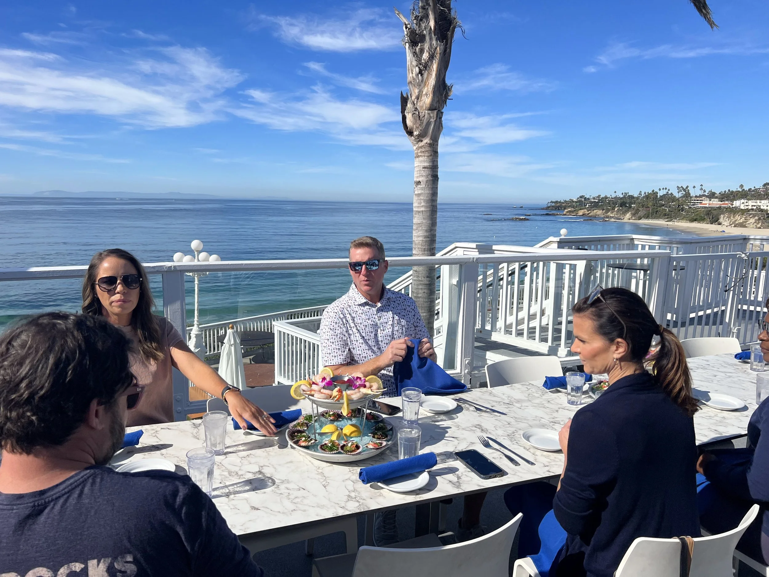 Food tour guests sharing a seafood tower at an oceanfront terrace table
