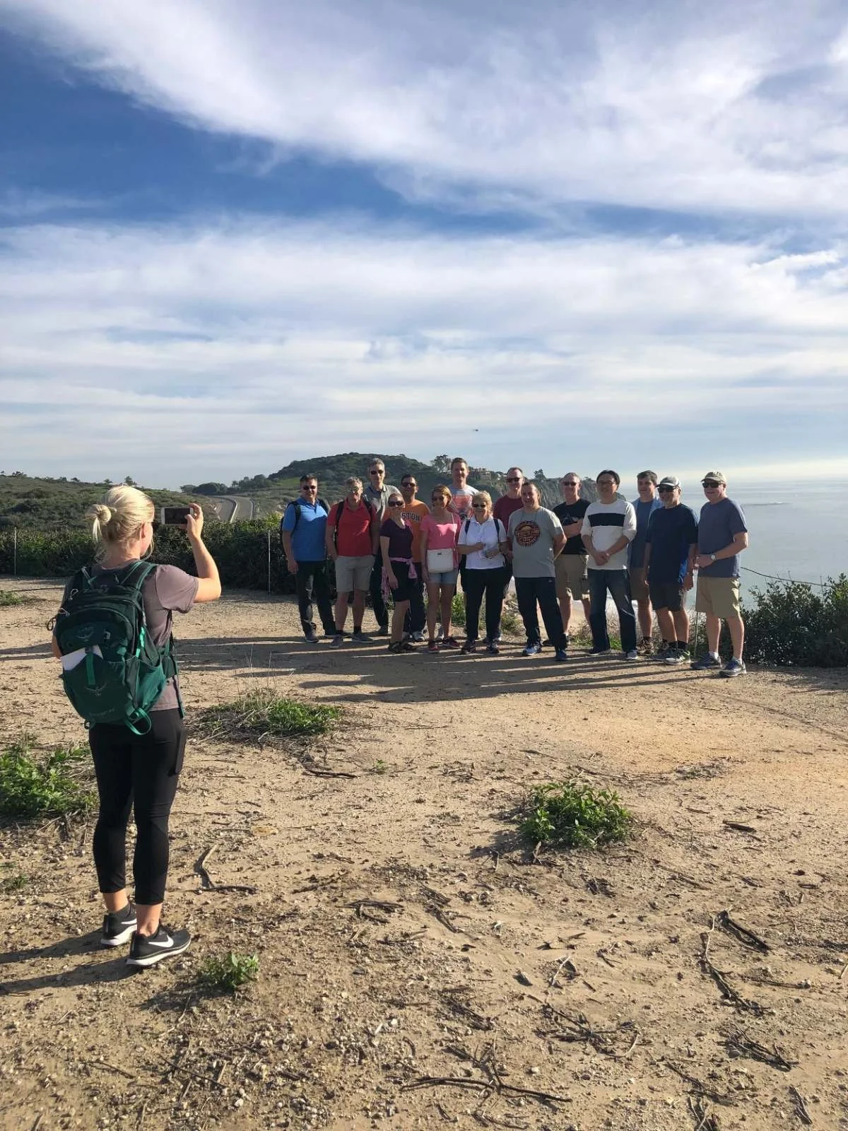 Guide photographing a corporate group on a coastal bluff trail