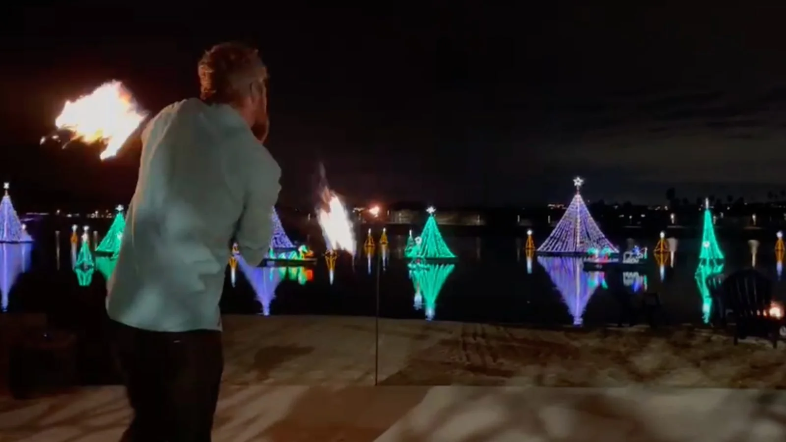 Fire performer at a nighttime beach event with lit decorations