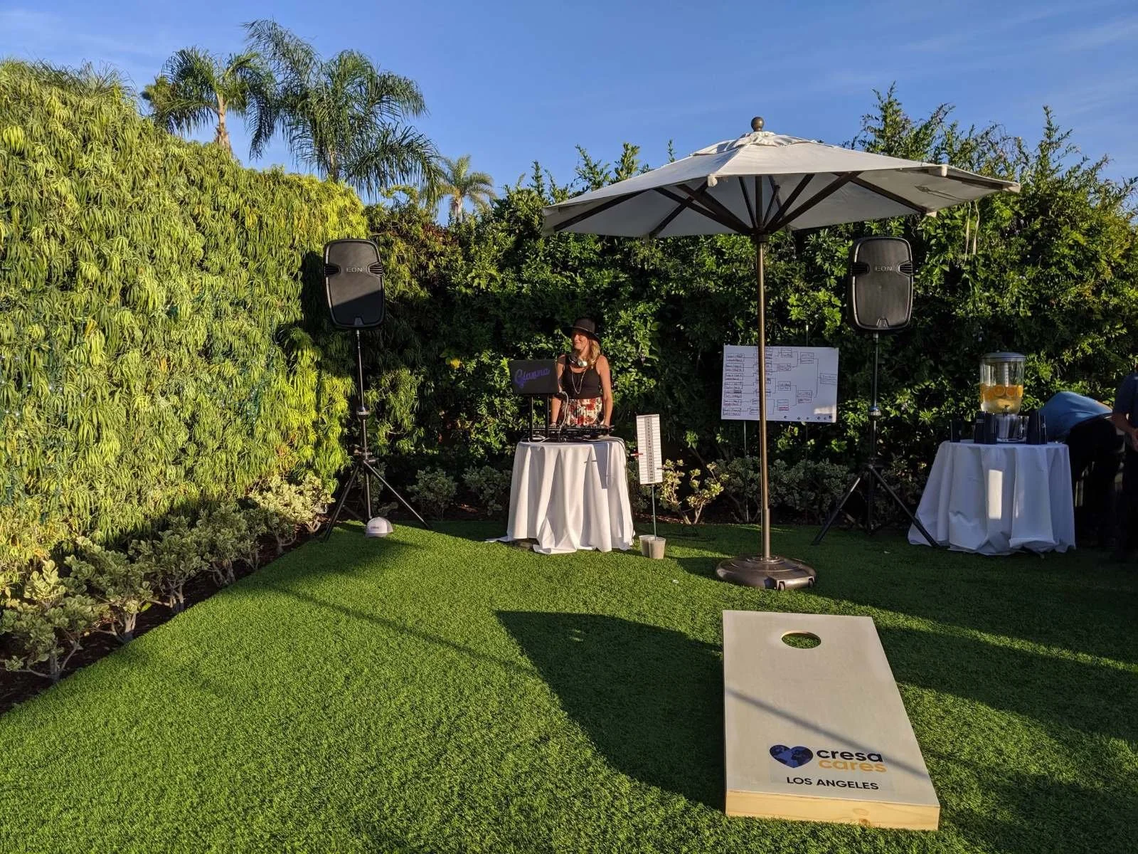 Garden event setup with cornhole and a shaded bar