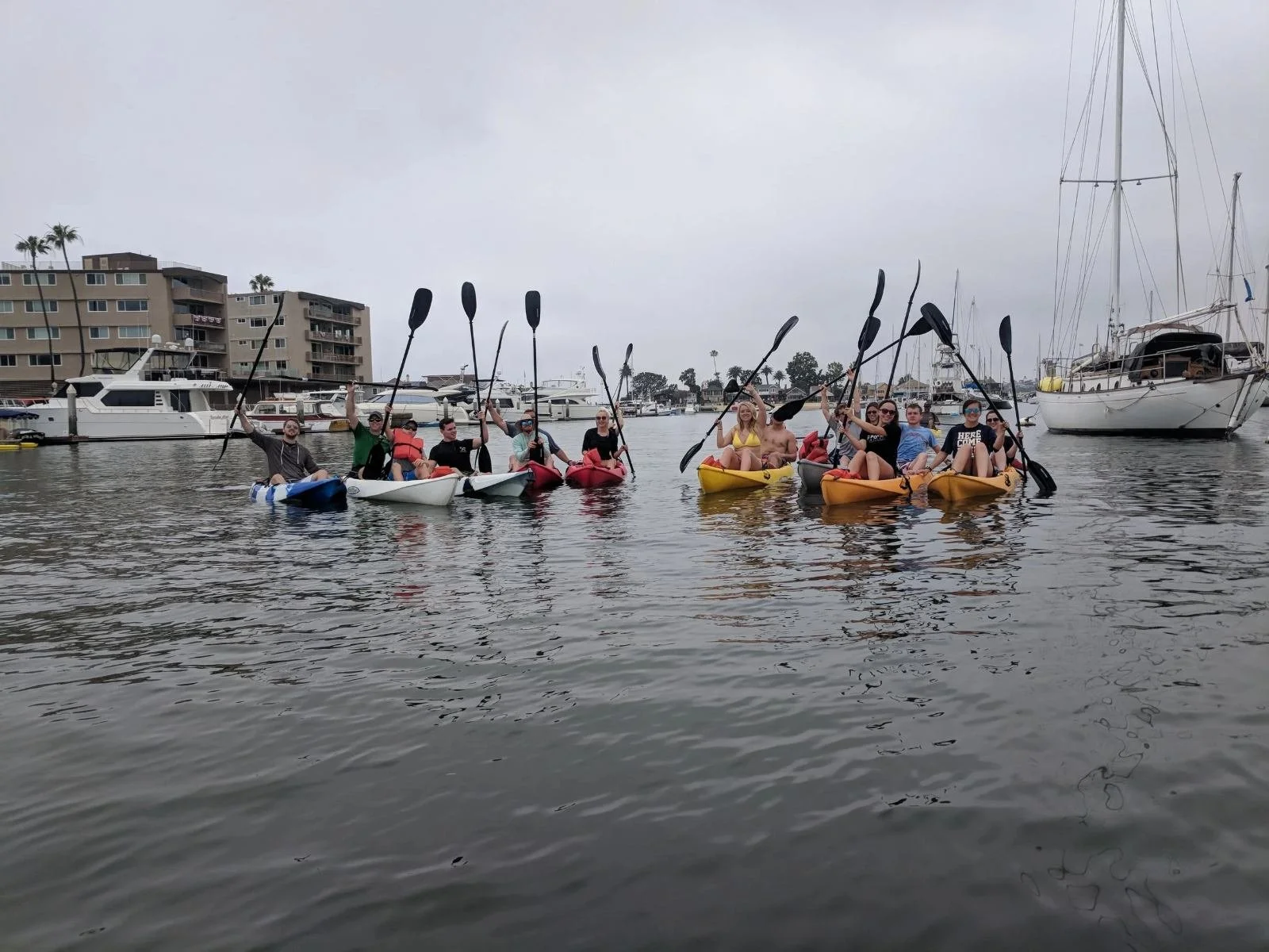 Kayakers and paddleboarders raising paddles in the harbor