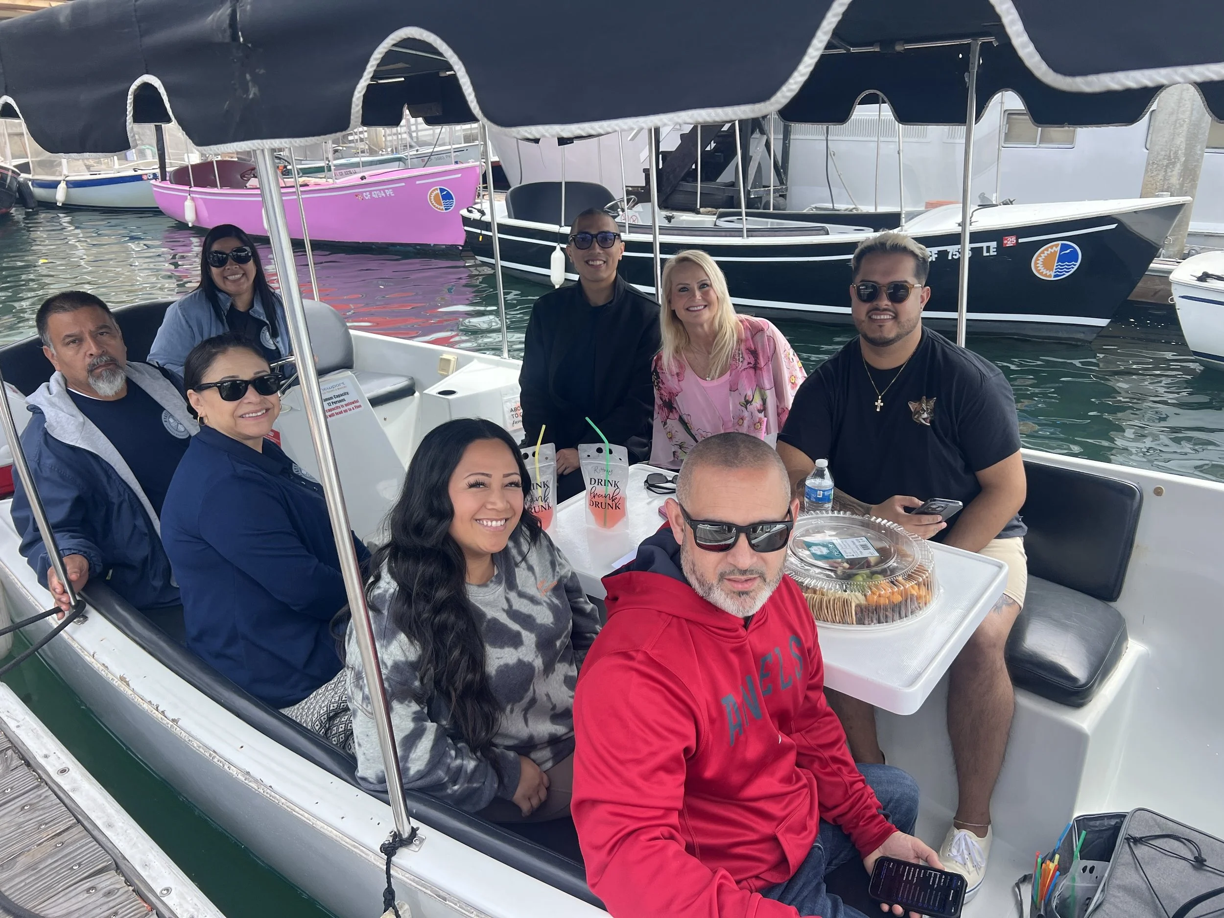 Team sharing food and drinks on a Duffy electric boat in Newport Harbor