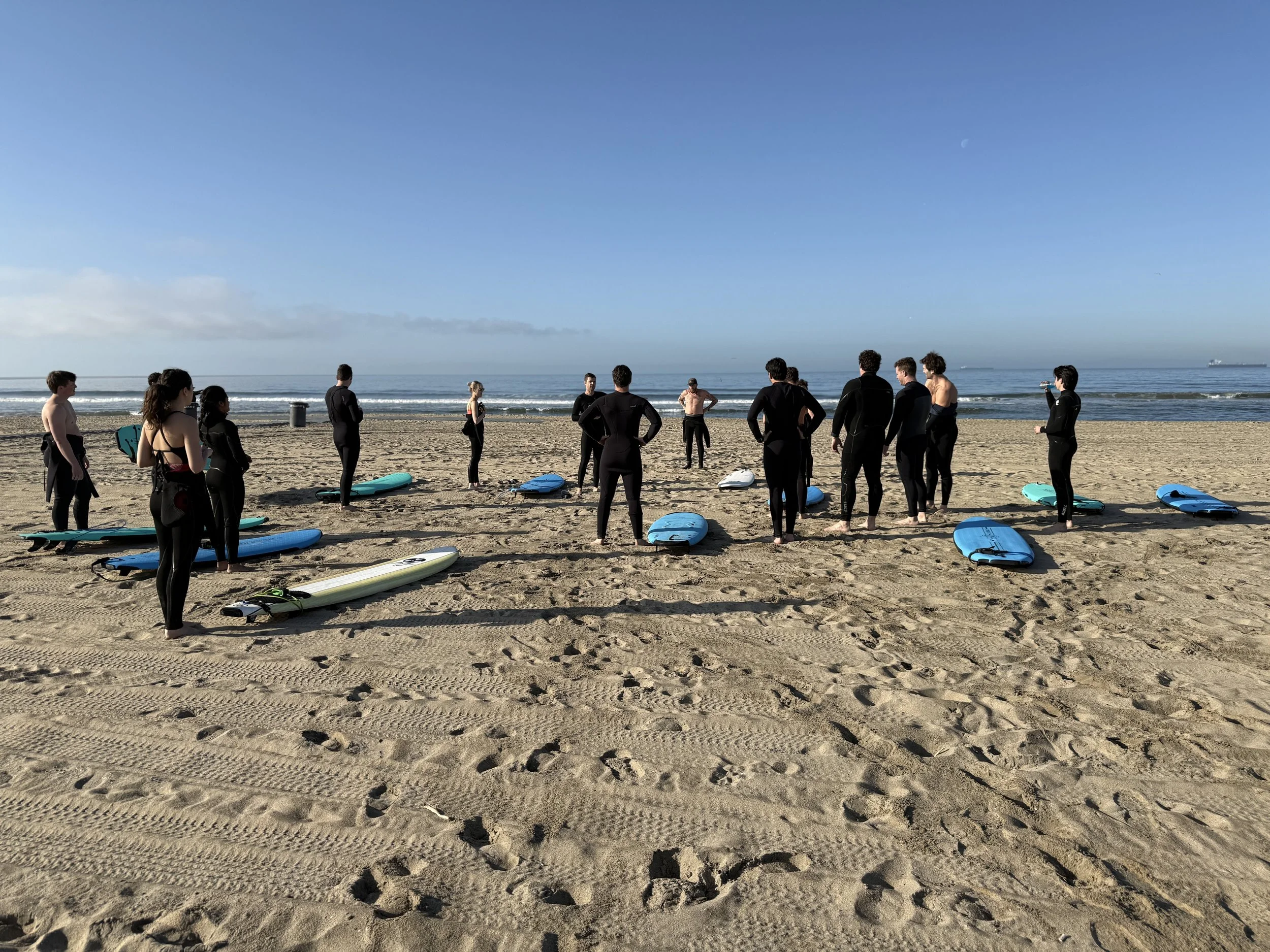 Surf lesson group stretching with boards in Huntington Beach