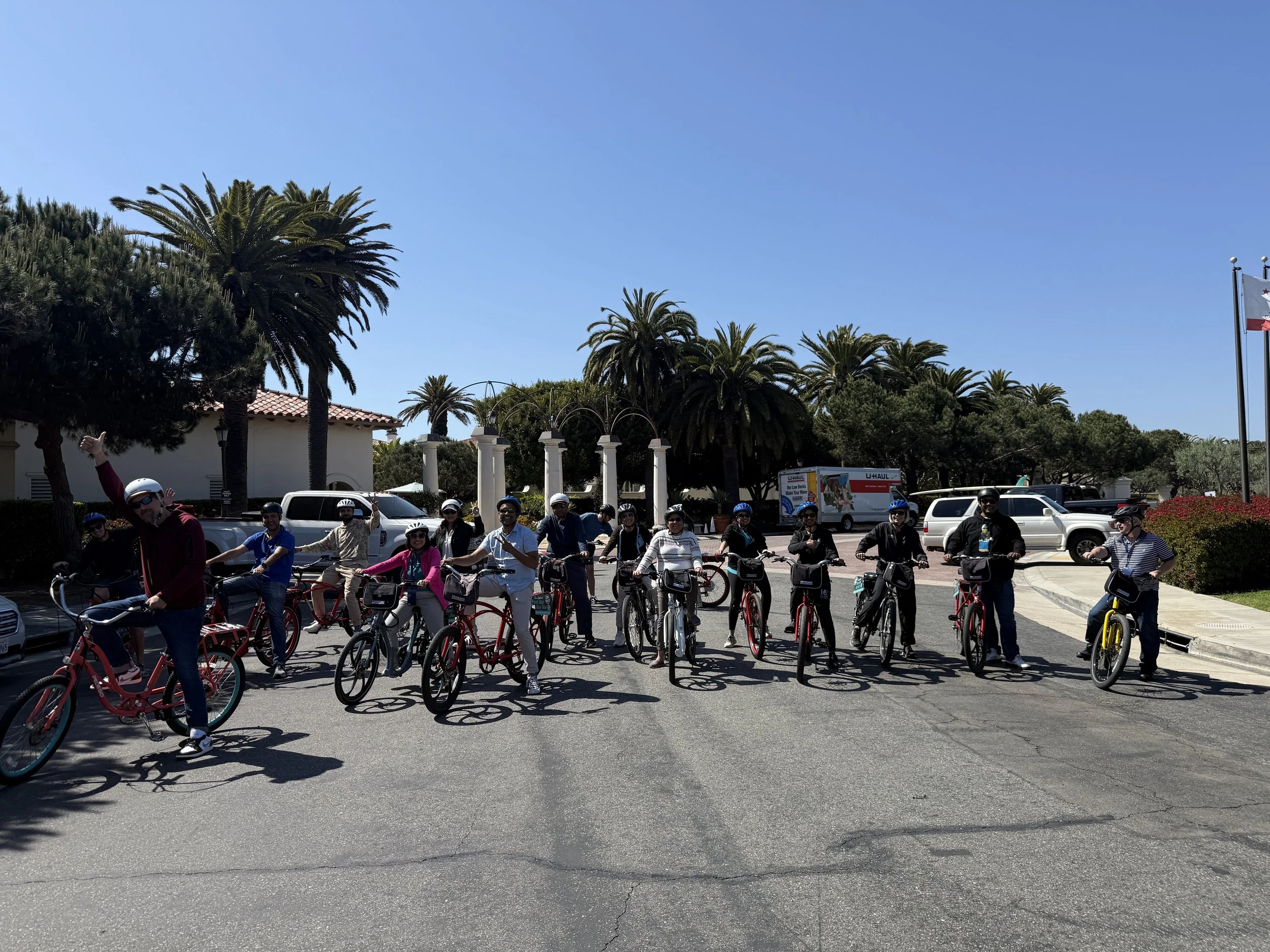 eBike tour group lined up with their bikes on a sunny street under palm trees