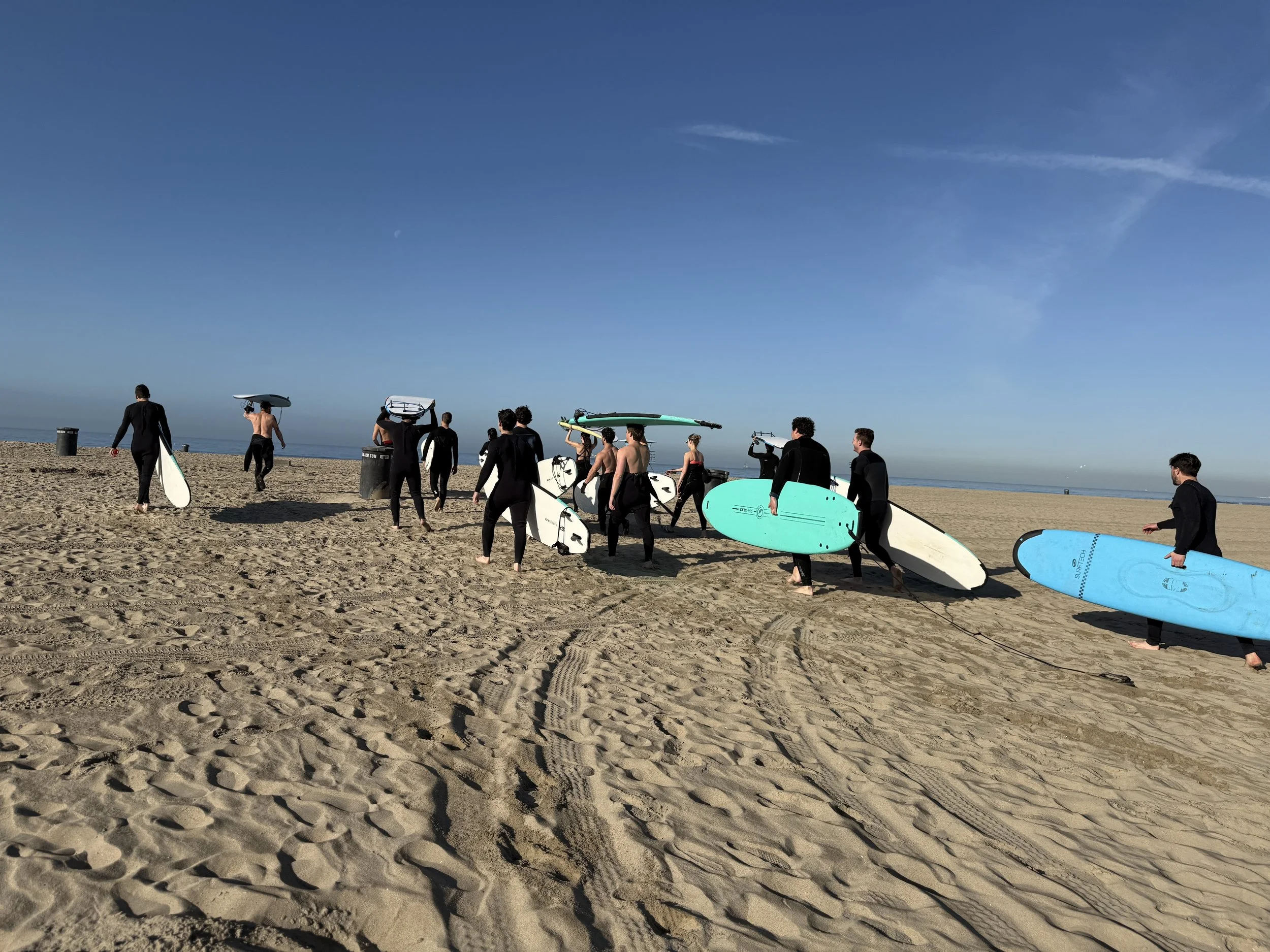 Corporate surf group carrying boards on Huntington Beach