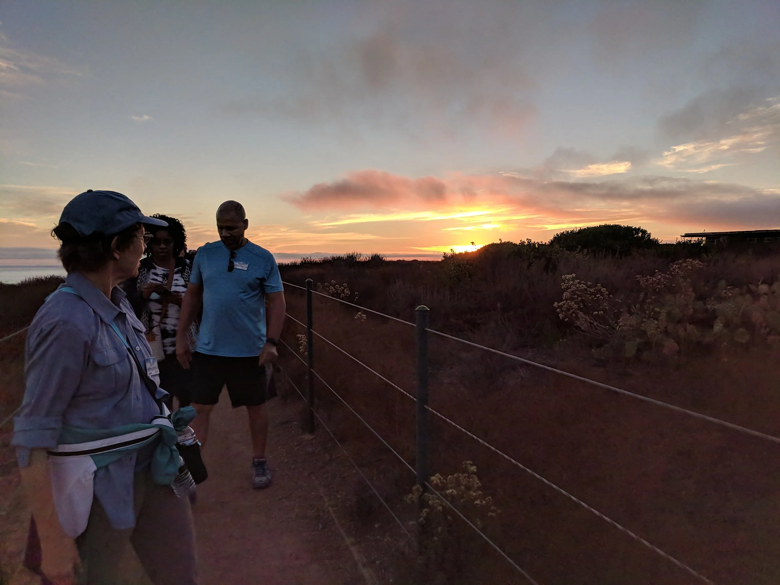 Team hiking a Dana Point bluff trail at sunset