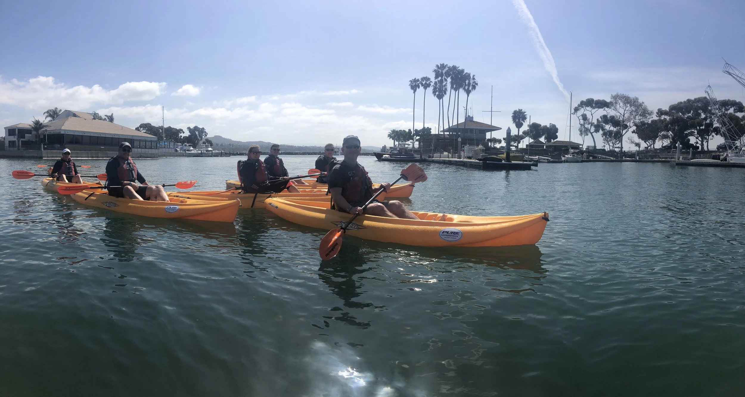 Orange tandem kayaks lined up for a team paddle in Dana Point Harbor