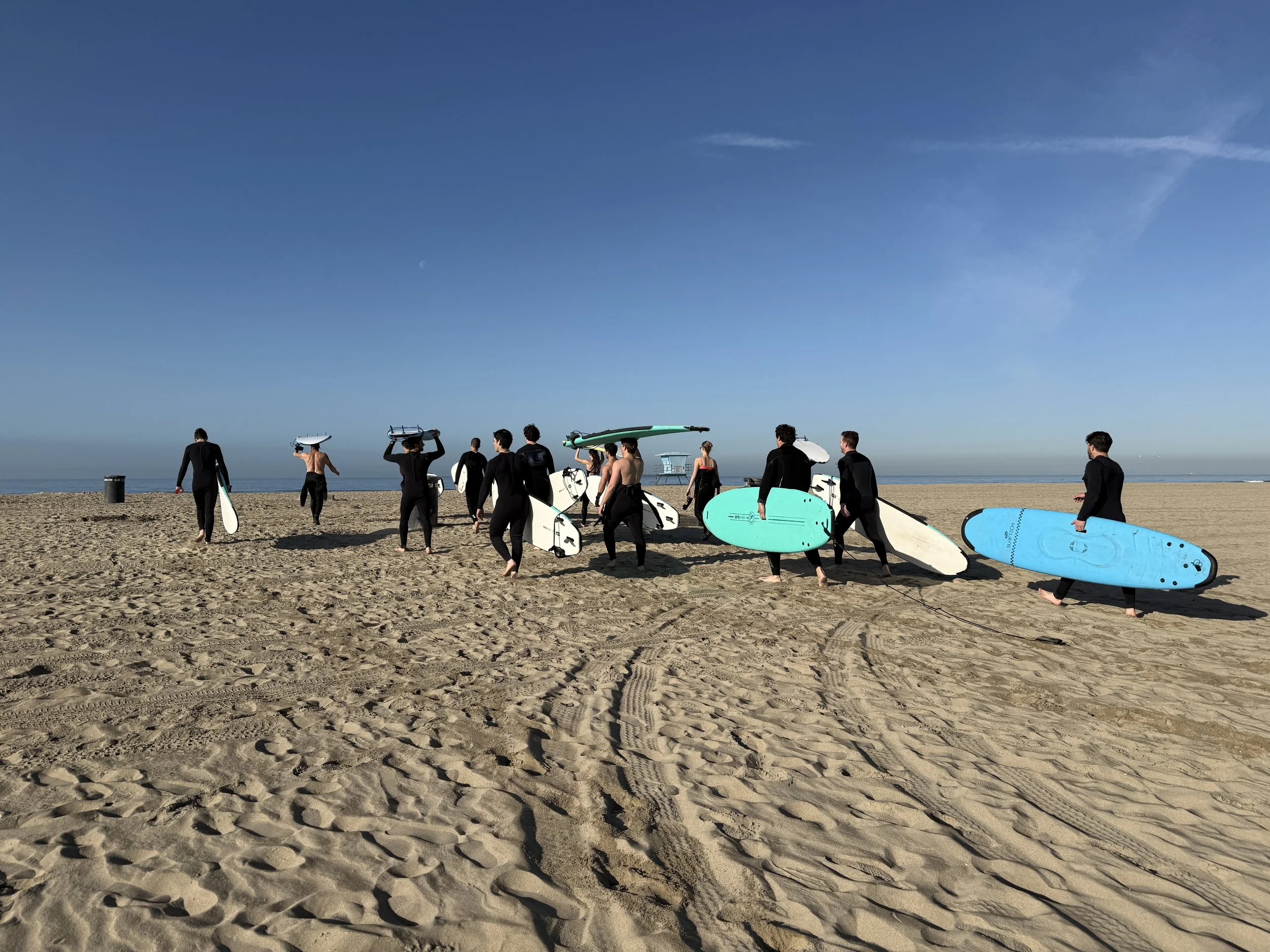 Team warming up on the sand before a Huntington Beach surf lesson