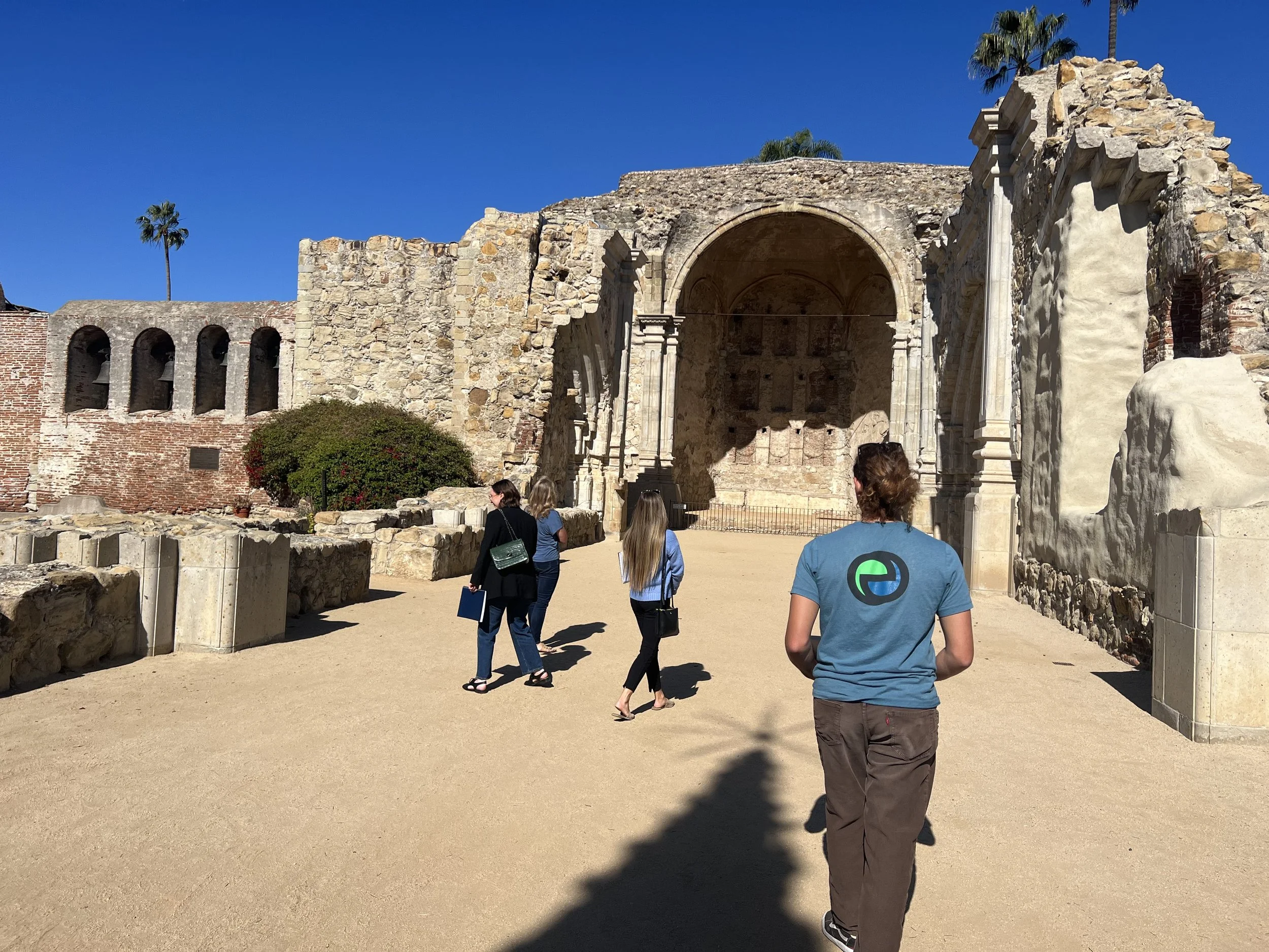 Group walking past the Mission San Juan Capistrano ruins