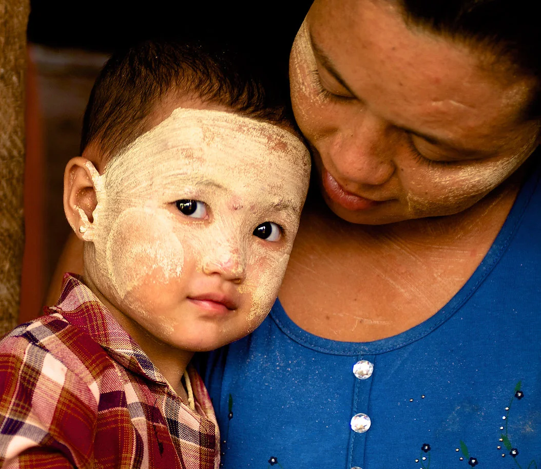 Myint Kaing looks affectionately at her daughter outside their Shwebo home. In addition to making her design, she also feeds her baby Thanaka liquid twice daily to ensure good health.