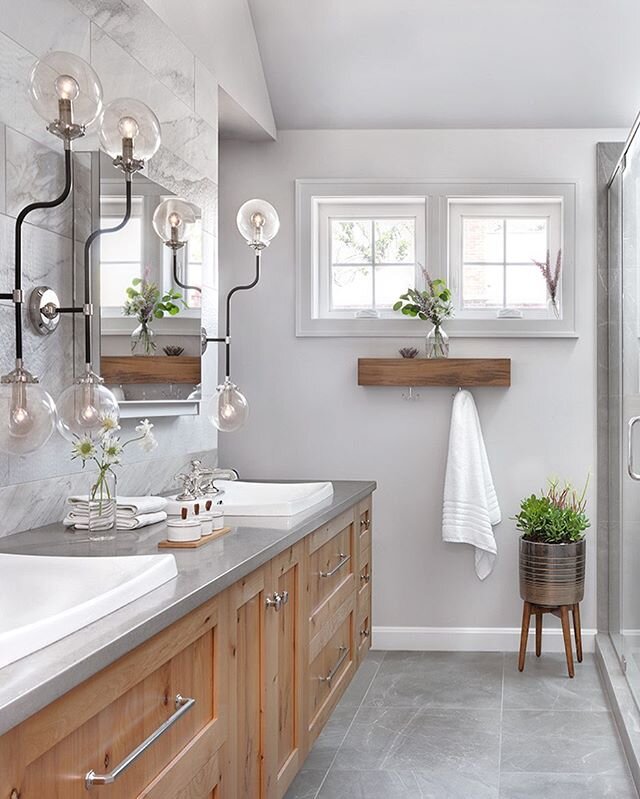 Clean, natural tones paired with fun lighting fixtures and pretty plants; we are slightly obsessed with this bathroom by @castledesignstl . 💡🌿