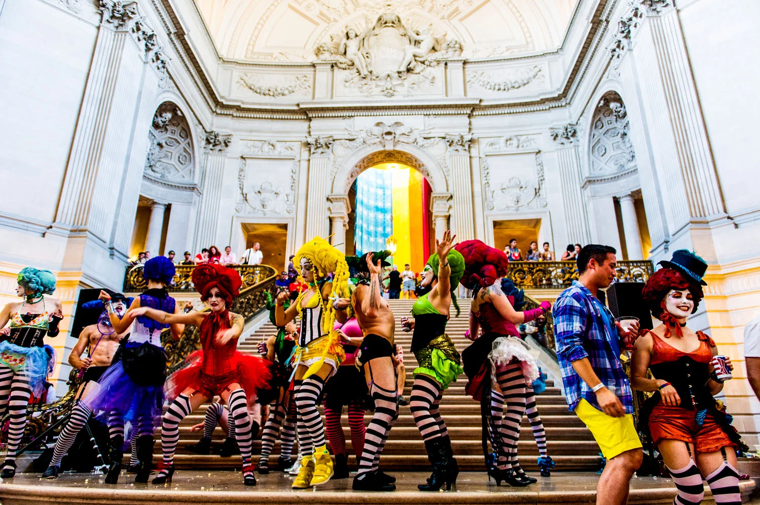 Costumed people dance on city hall steps at gay pride parade