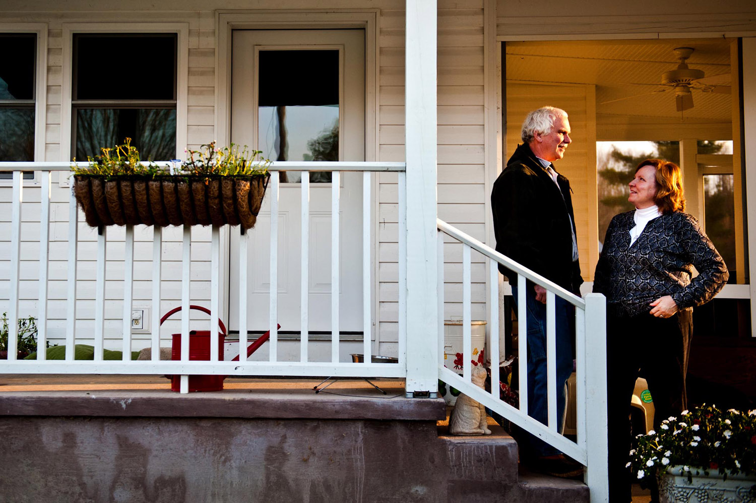 Man and woman talk on front porch steps