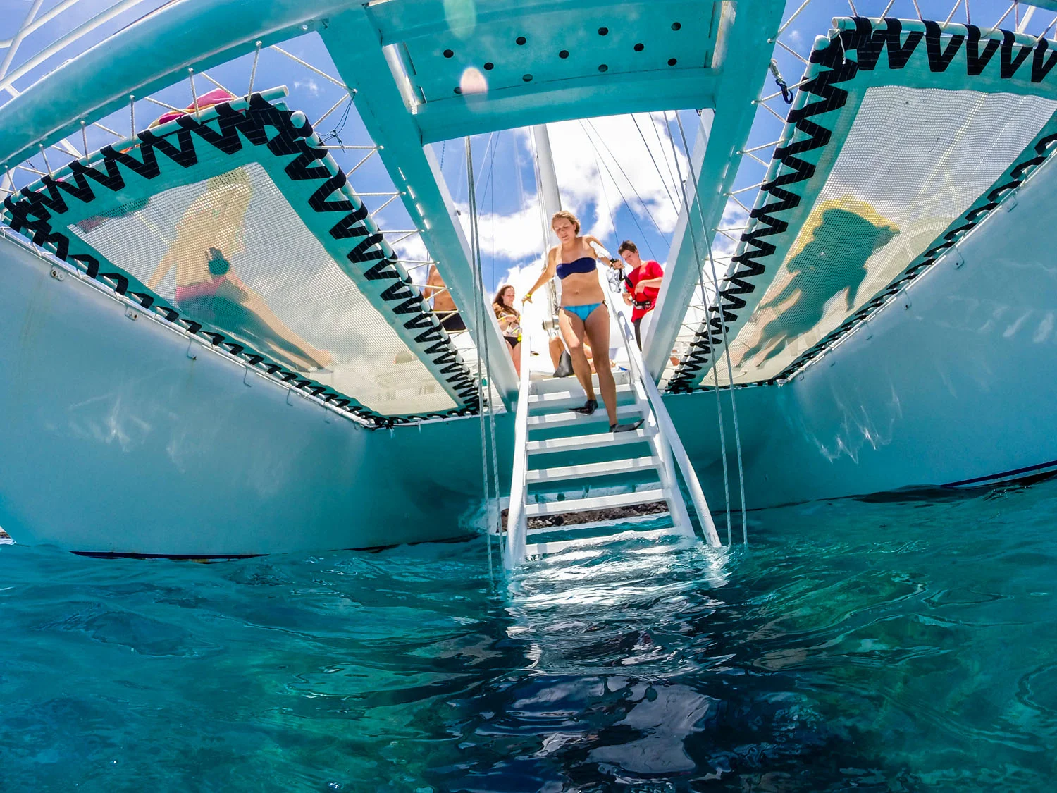 Girl in bikini walks down sailboat steps into the water
