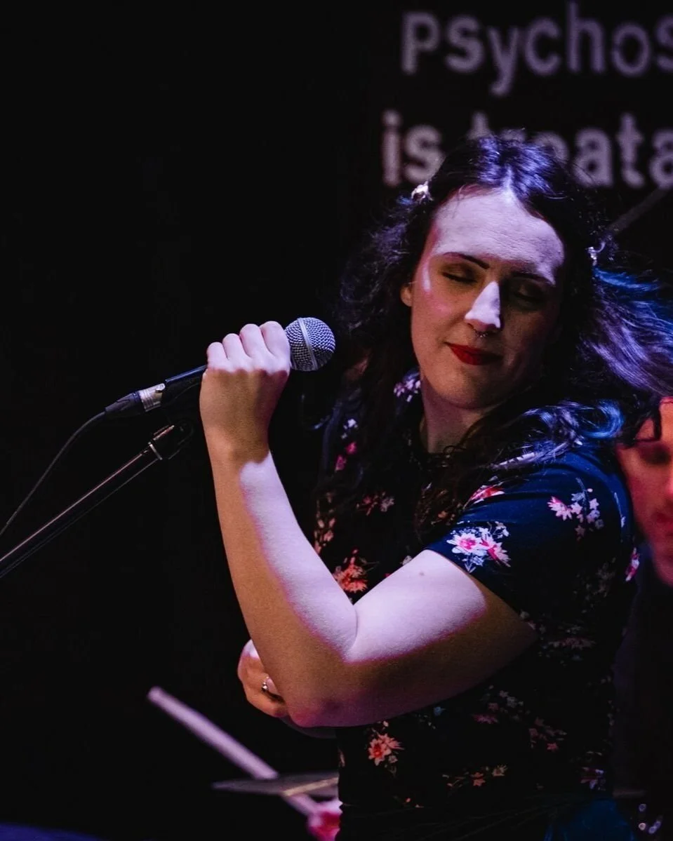 Sarah holds a microphone at a Reach Out Psychosis show.