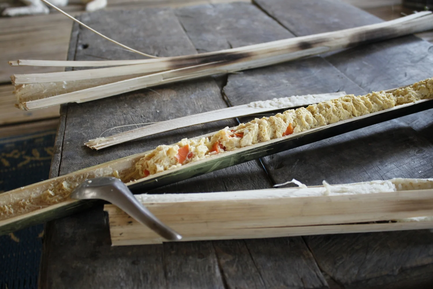 Sticky rice, eggs and vegetables cooked inside pieces of bamboo