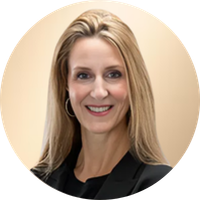 A blonde woman smiling, wearing a black blazer, against a beige background.