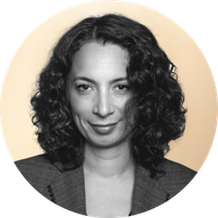 Black-and-white portrait of a woman with shoulder-length curly hair, wearing a blazer, smiling slightly.