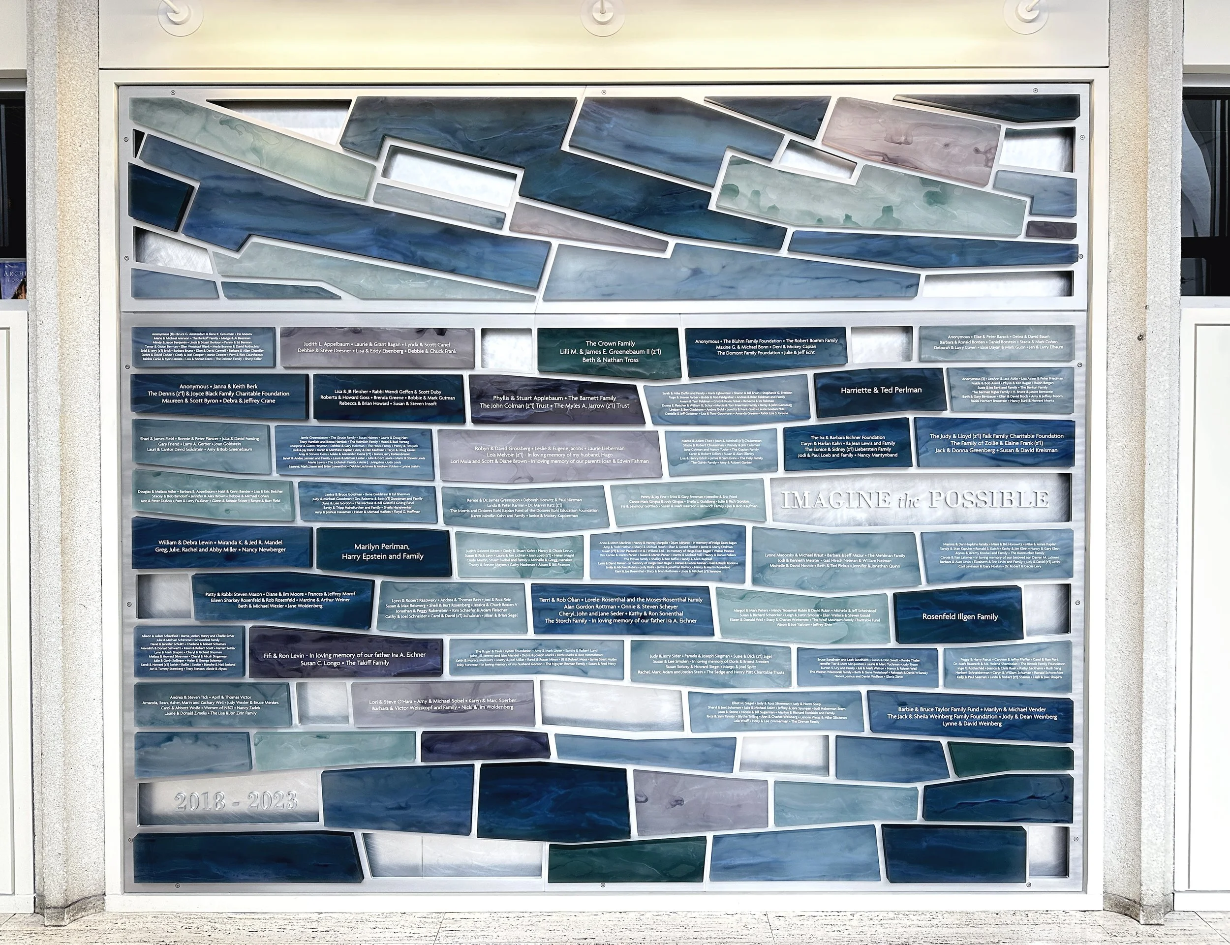 Large modular donor recognition wall with blue and teal resin donor panels and dimensional architectural detailing.
