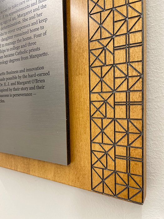 Custom wood and metal detail featuring engraved geometric patterning and dimensional fabrication.