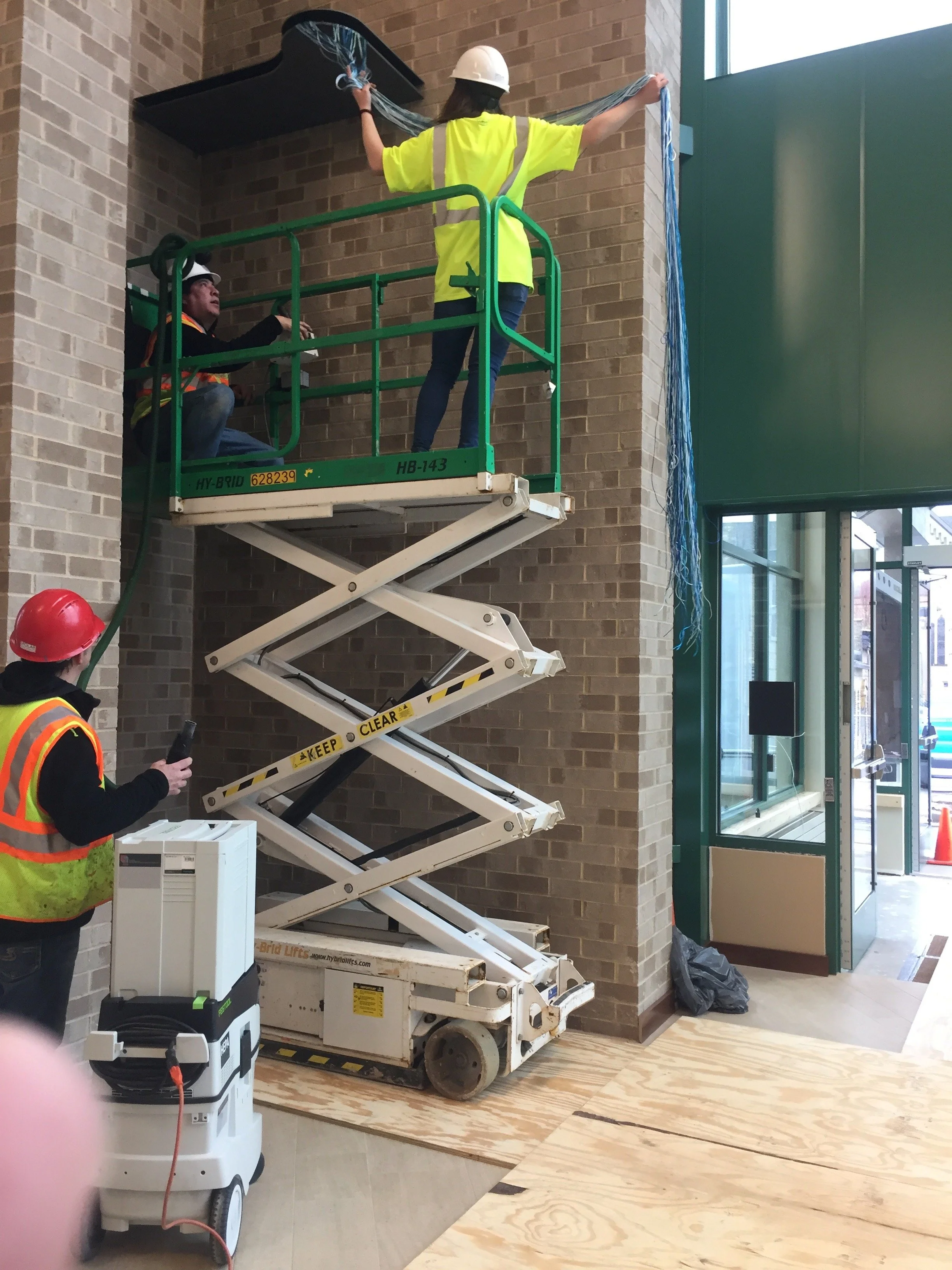 Spolar Studio installation team mounting a custom architectural feature in a tall interior space.