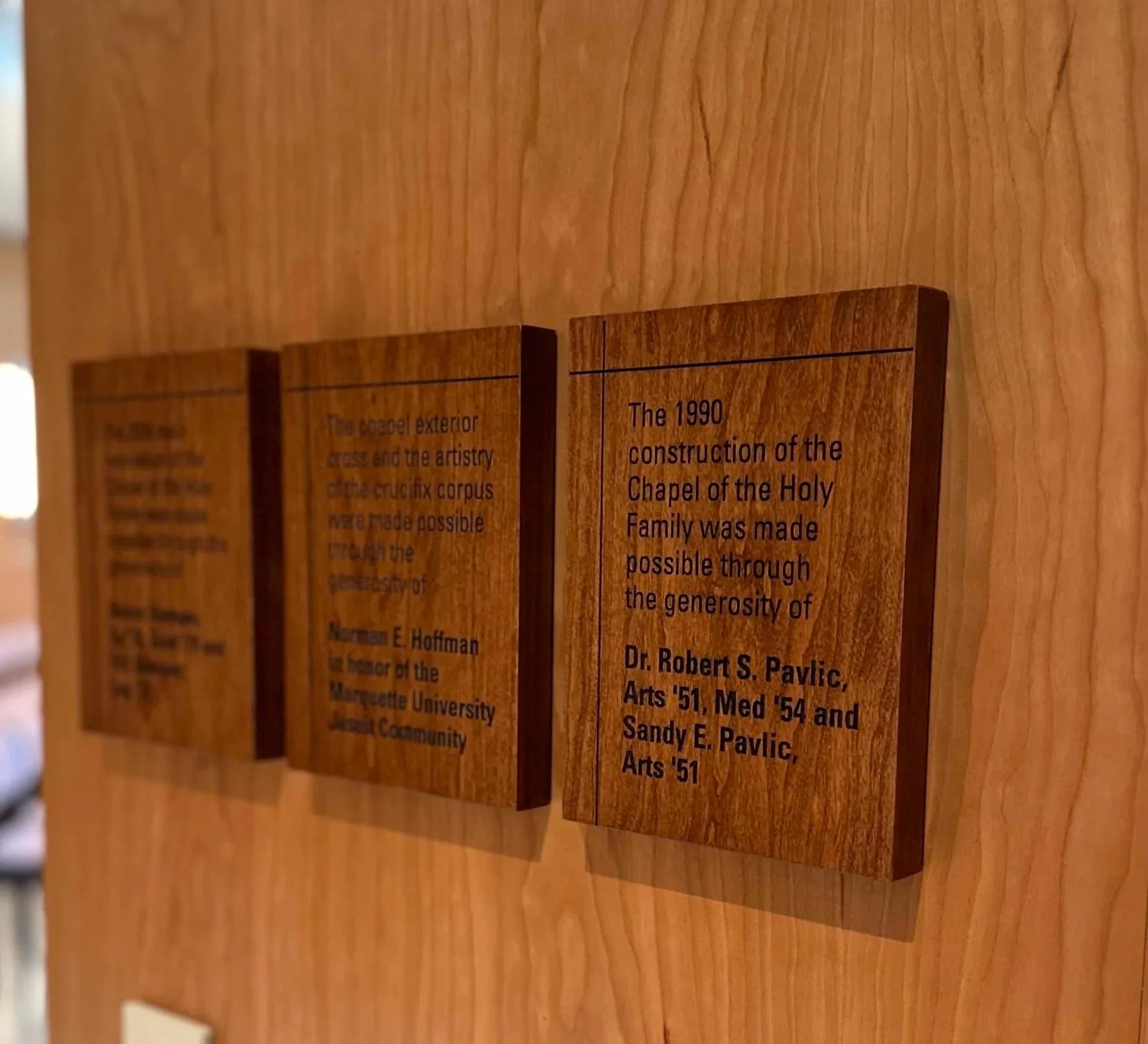 Individual engraved wood recognition plaques mounted to a finished wood wall.