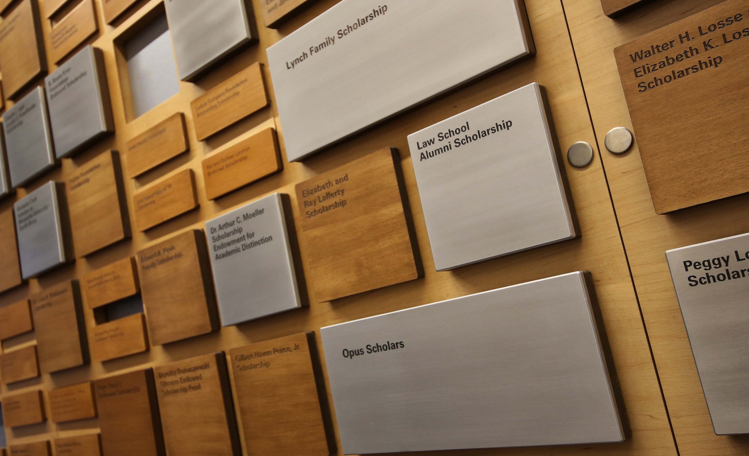 Custom donor recognition wall featuring dimensional wood and metal plaques in a modular grid.