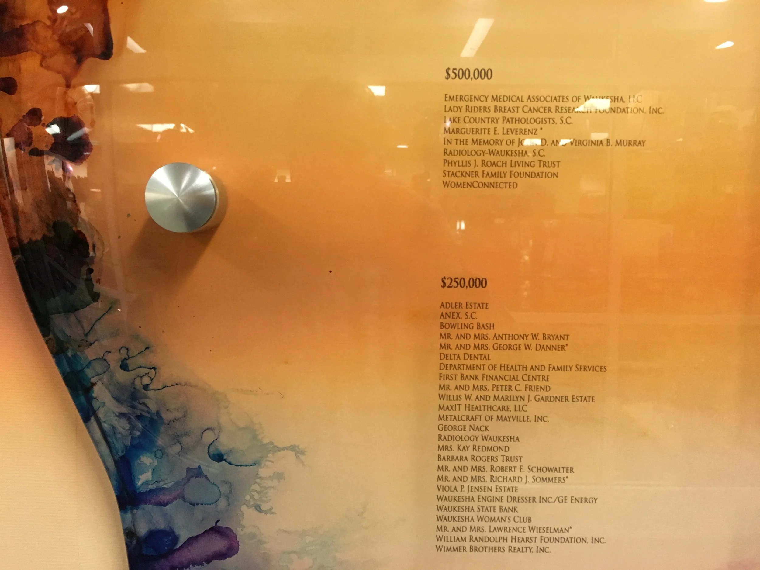 Donor names and giving levels printed on a resin recognition panel with dimensional hardware.