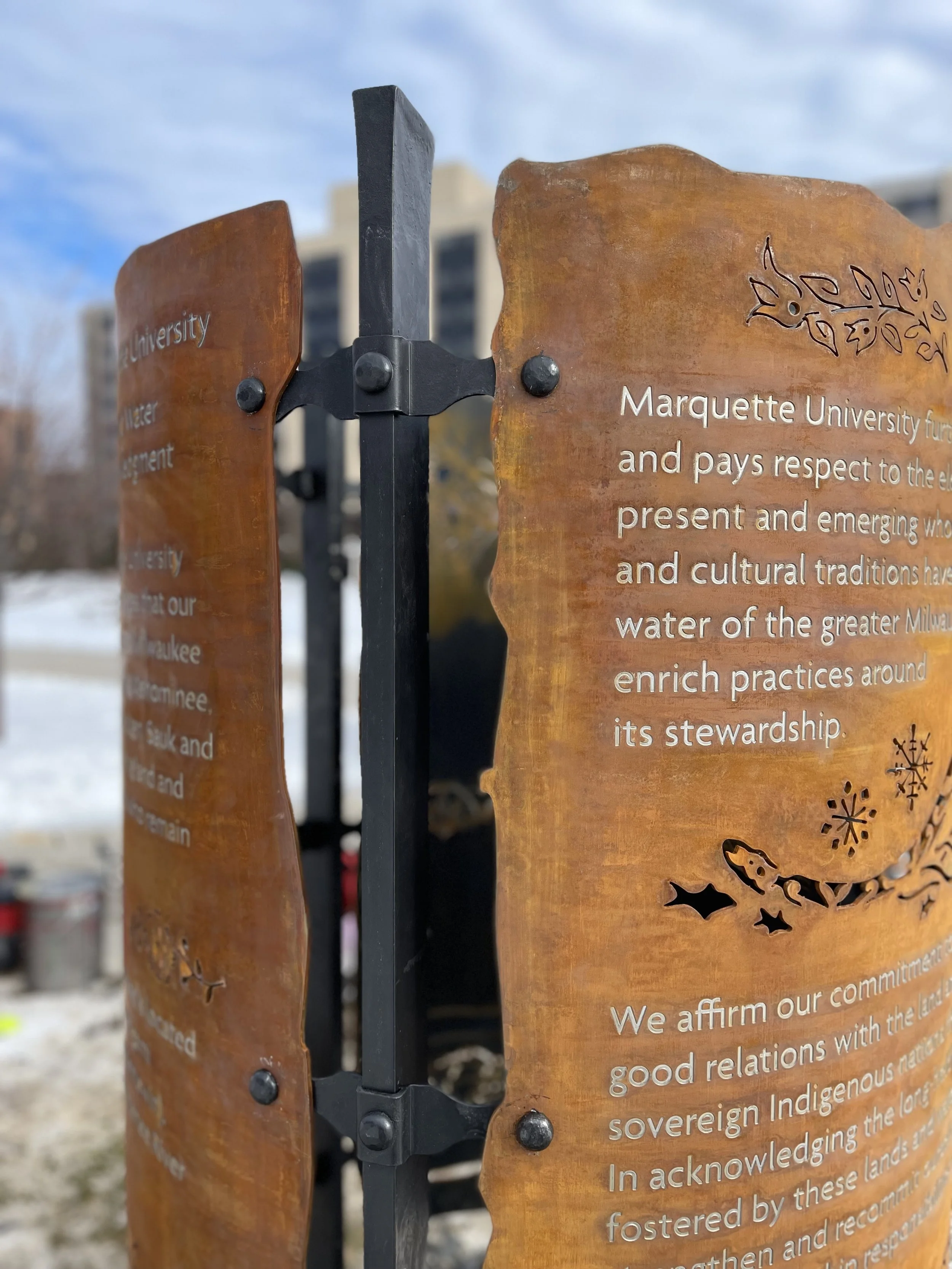 Close-up of custom weathered steel panels with cut graphics, engraved text, and fabricated metal hardware.