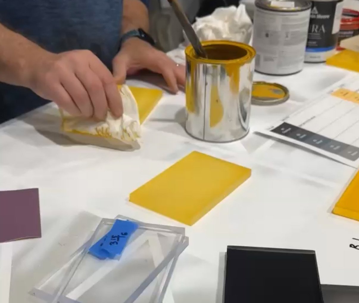 Hands testing paint and stain samples for color and finish selection.
