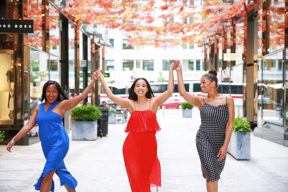  3 Black women smiling holding hands facing the camera in City Center, Washington, D.C.  Photos:  Milli Mike / Millgrimage  