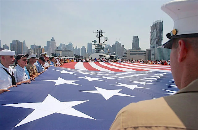 New York (May 29, 2006) - Marines, Sailors, Soldiers, Airmen, Coast Guardsmen and military veterans display the American flag during the playing of taps on the deck of the museum and display ship USS Intrepid, during a Memorial Day Commemoration at Fleet Week 