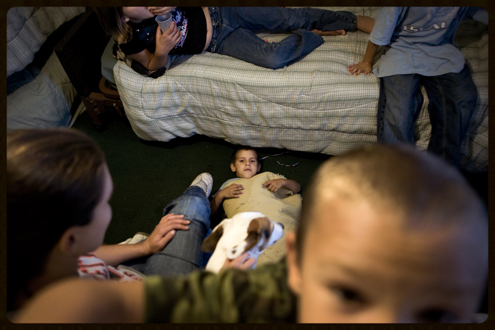 "Broken Dreams: The Great Recession Hits Ohio" - Nicole, Taylor, Anthony, Nicolas, and Ethan Farnsworth hang out in their dorm room on a Saturday afternoon at the Cornerstone Ministry and Homeless Shelter in Marietta, Ohio. The family of six lives in one room in the shelter. The heartland of America was hit hard by the Great Receession -- the aftershocks of the economic downturn could be seen across the state of Ohio, with the already-poor sinking into poverty, low-wage job holders becoming unemployed, and marginally housed becoming homeless. PHOTO CREDIT: KAYANA SYYMCZAK