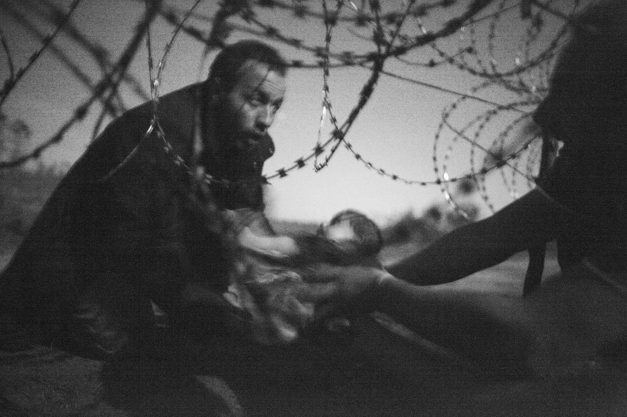 Photograph by Warren Richardson. A man passes a baby through the fence at the Hungarian-Serbian border in Röszke, Hungary, Aug. 28, 2015.