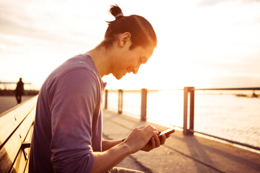 getty young man using smartphone in park at sunset.jpg