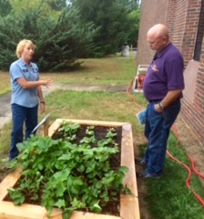 Kristin Noel (left) shows off the new raised garden beds at the Concord Treatment Plant. Biosolids soil fills the beds, growing flowers and vegetables.