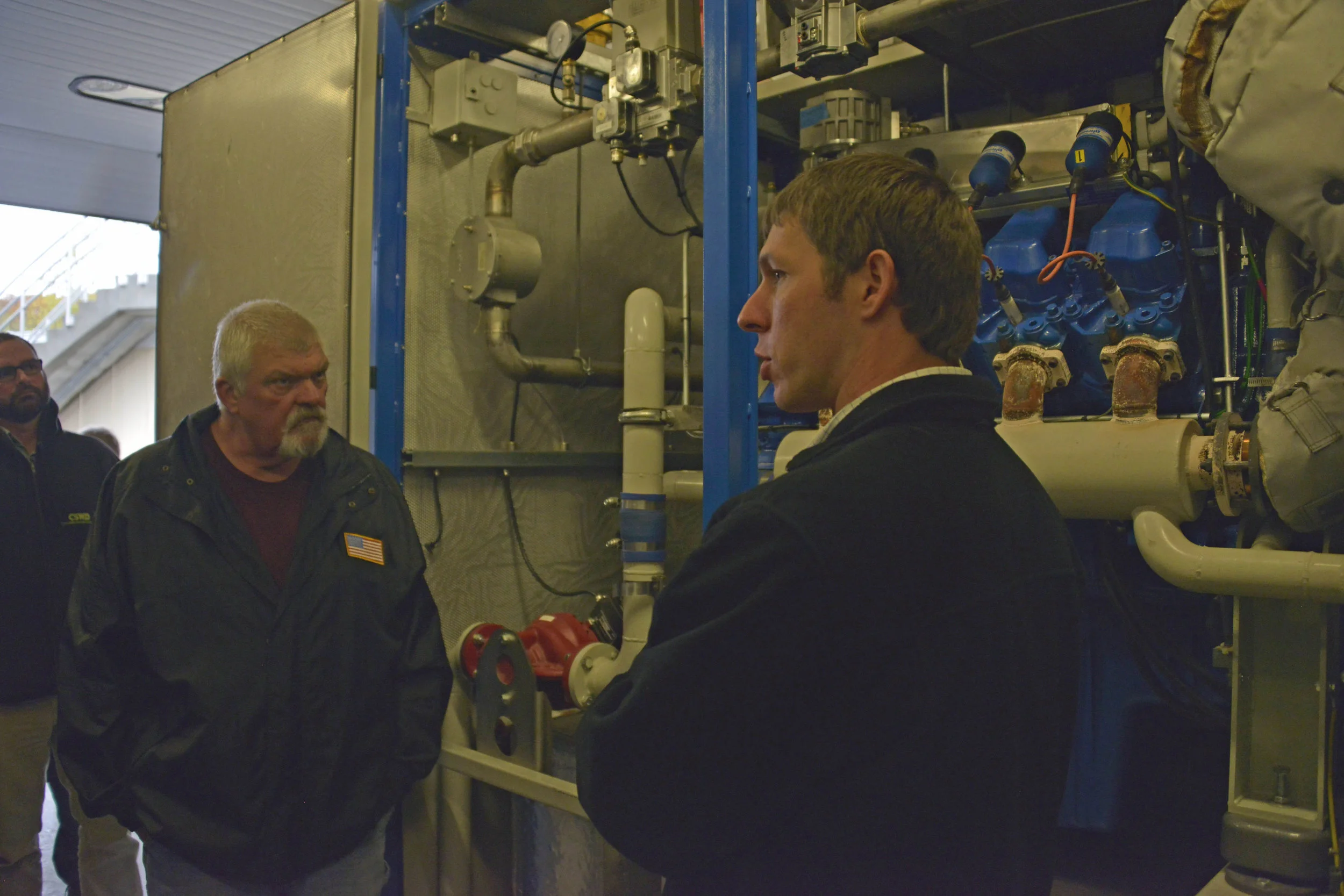 Travis Peaslee, Assistant Superintendent, right, explains the workings of the new engine generator at the LAWPCA CHP facility.