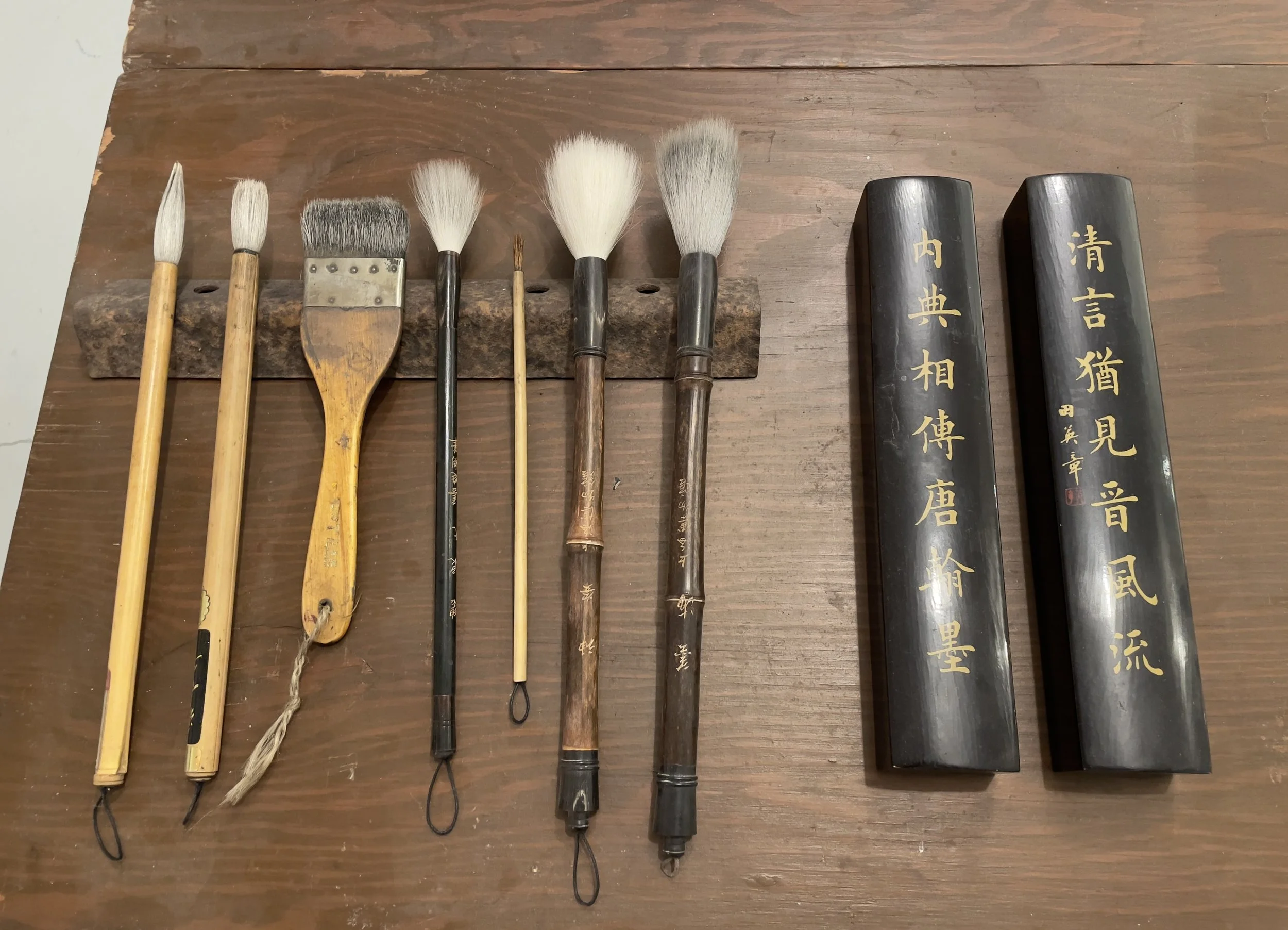 A collection of traditional calligraphy brushes and ink stones laid out on a wooden surface.